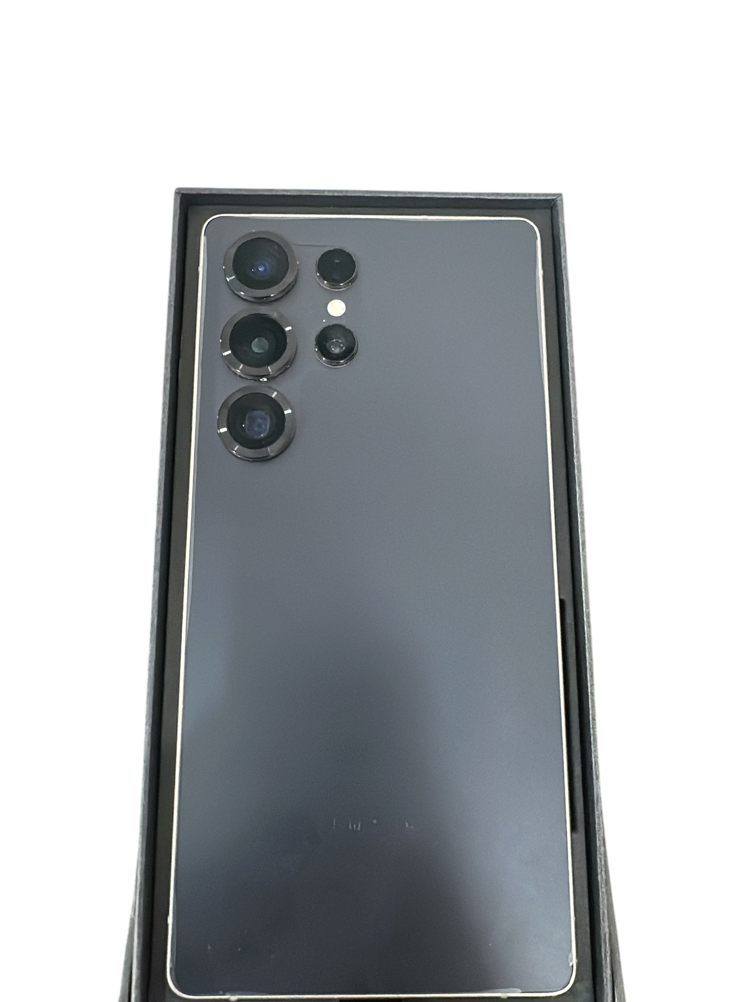 Iphoneio Official Galaxy S25 smartphone in dark grey with a multi-lens camera system inside its retail box