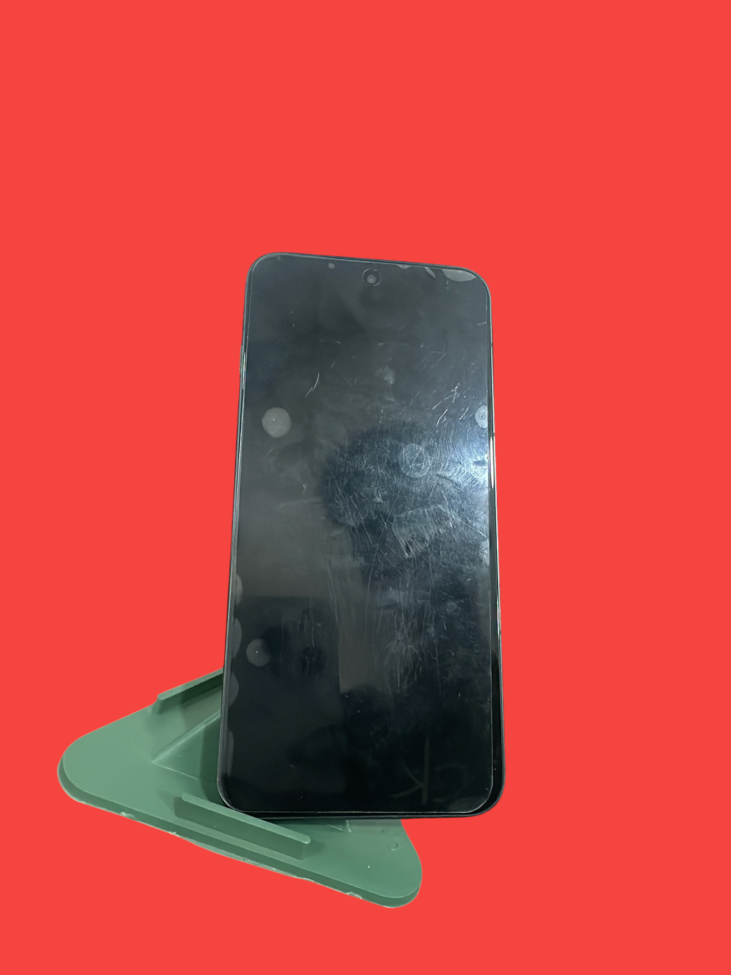 Iphoneio Official OnePlus Nord CE4 smartphone with a black screen resting on a green plastic stand