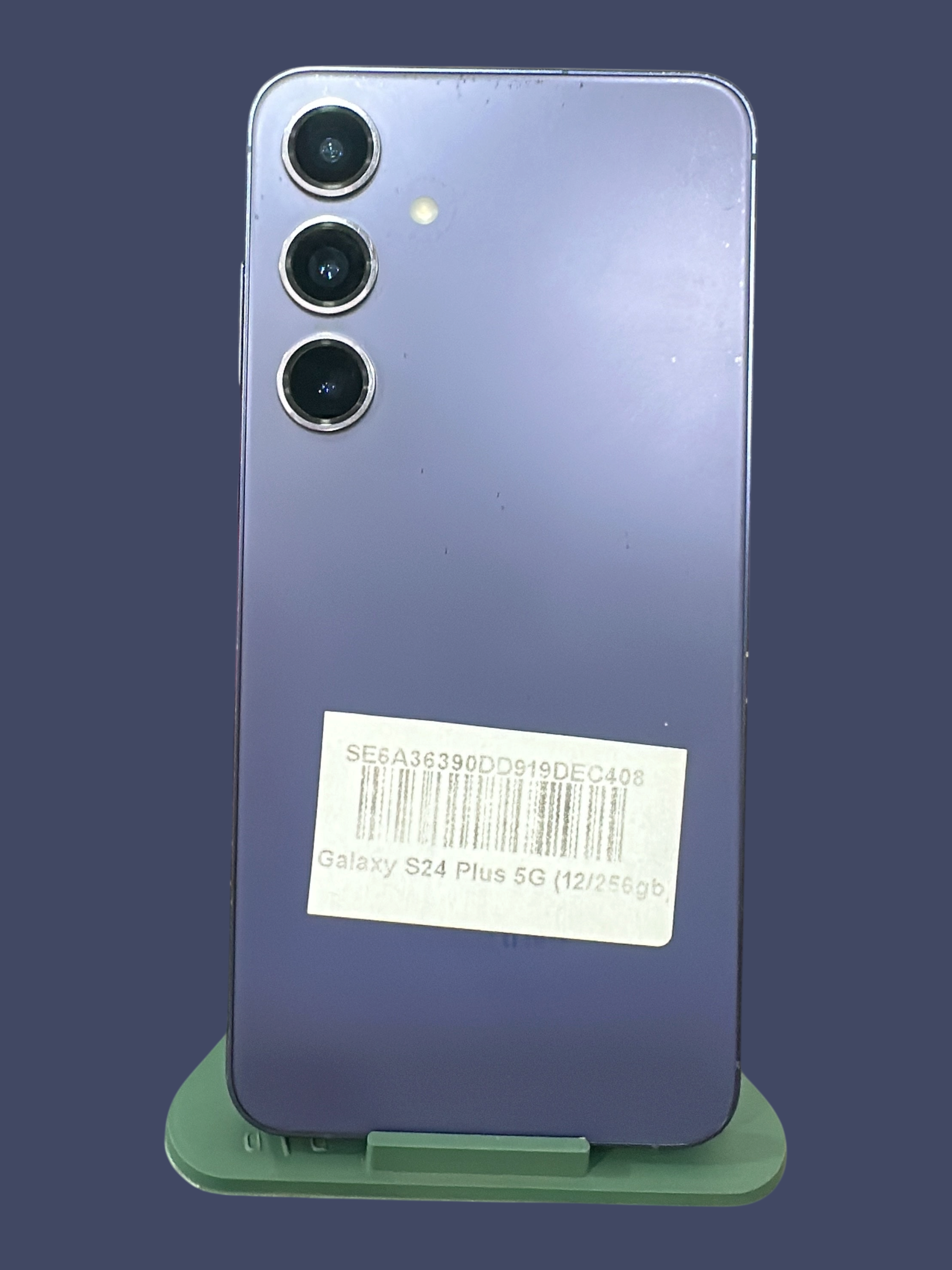 Iphoneio Official Samsung Galaxy S24 Plus 5G smartphone in purple with a triple camera system on a green stand.