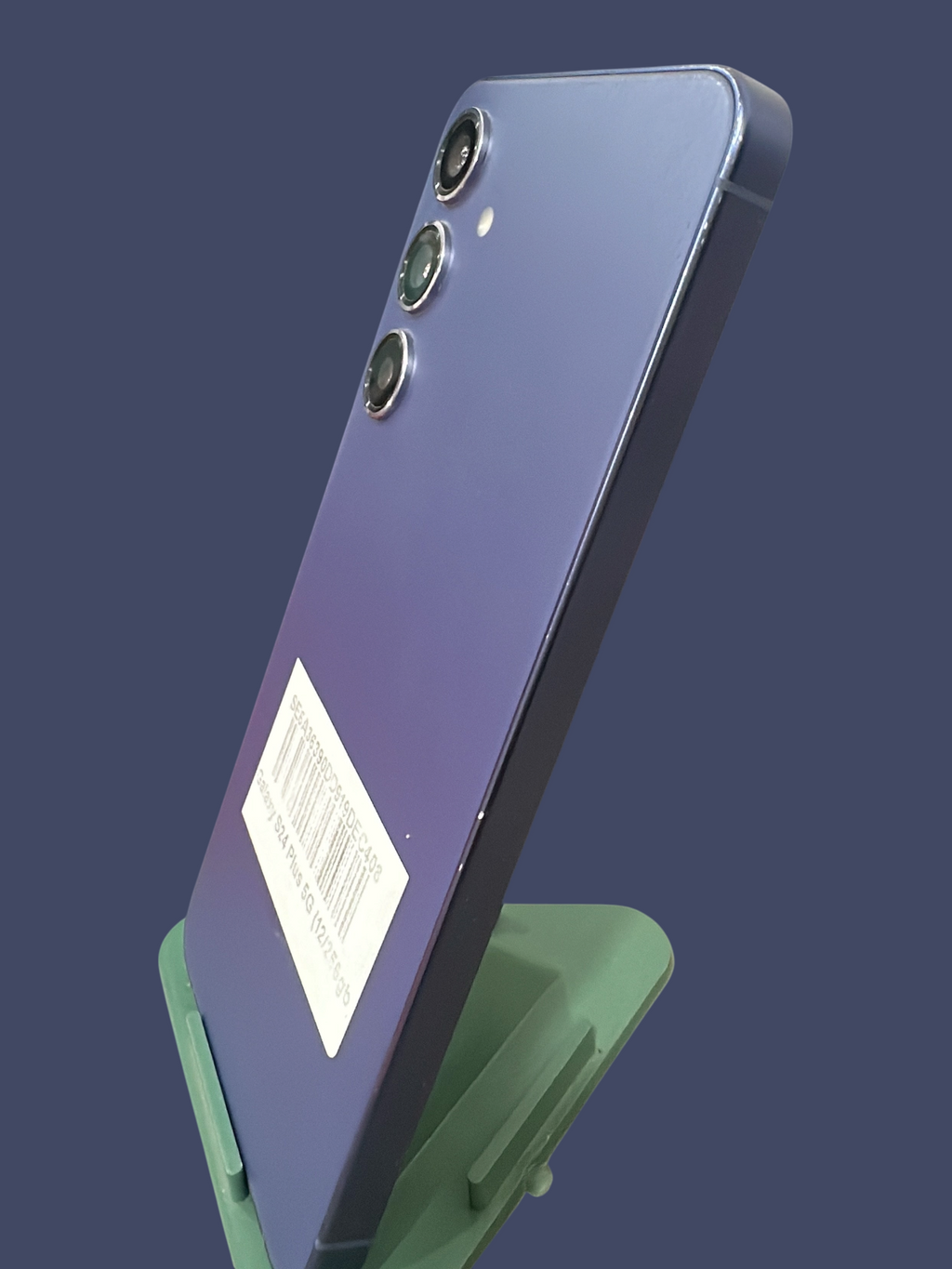Iphoneio Official Samsung Galaxy S24 Plus 5G smartphone in purple, shown from a side angle on a green stand.