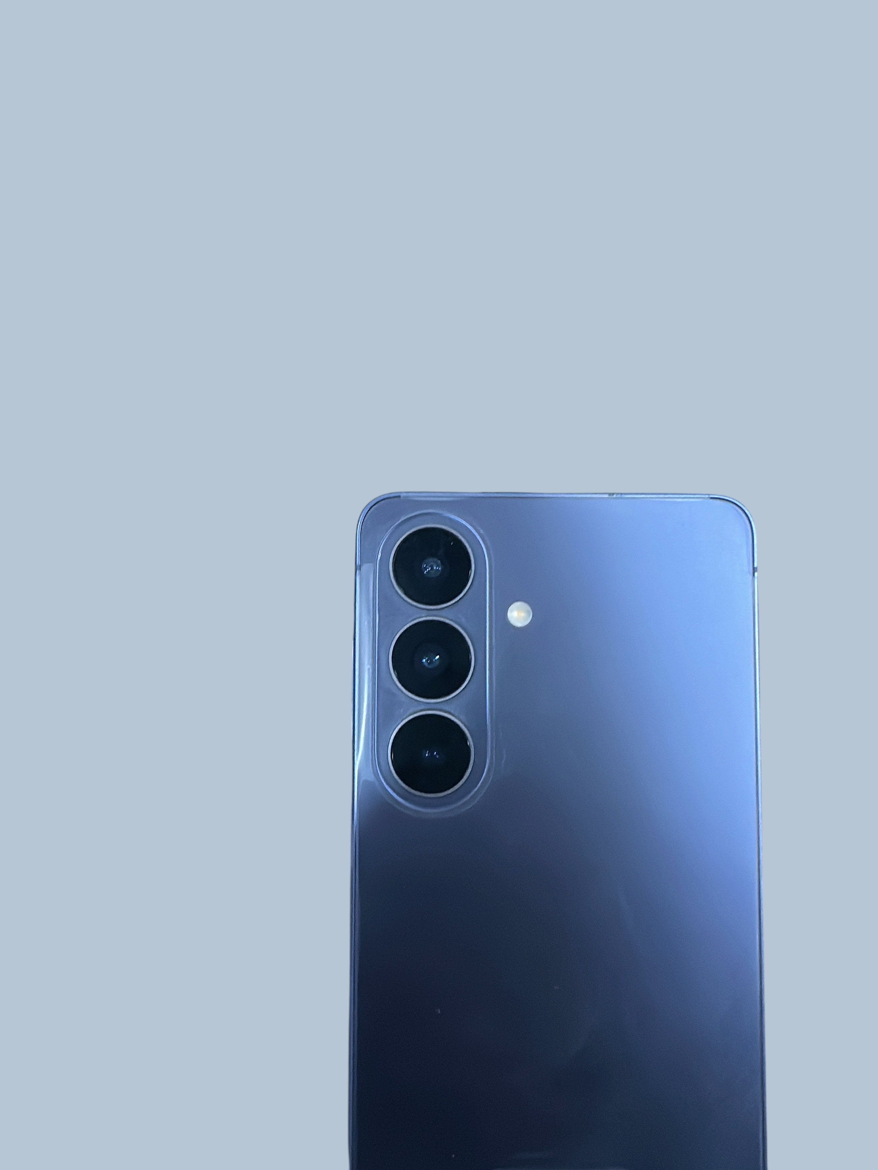 Iphoneio Official Samsung Galaxy S26 smartphone in blue with a triple-lens camera system next to its product box.