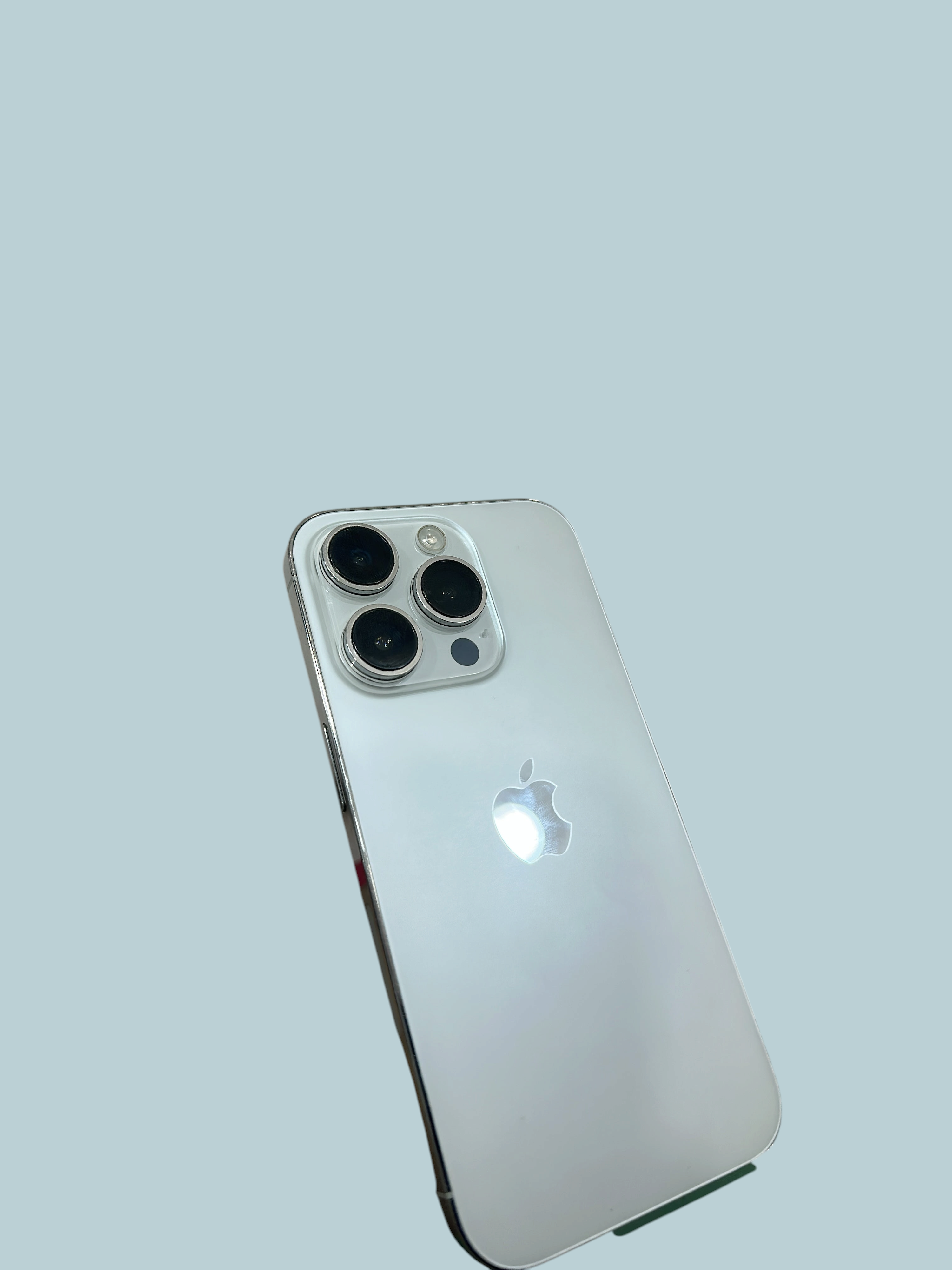 Iphoneio Official silver smartphone with a triple-lens camera system and a sleek glass back design.