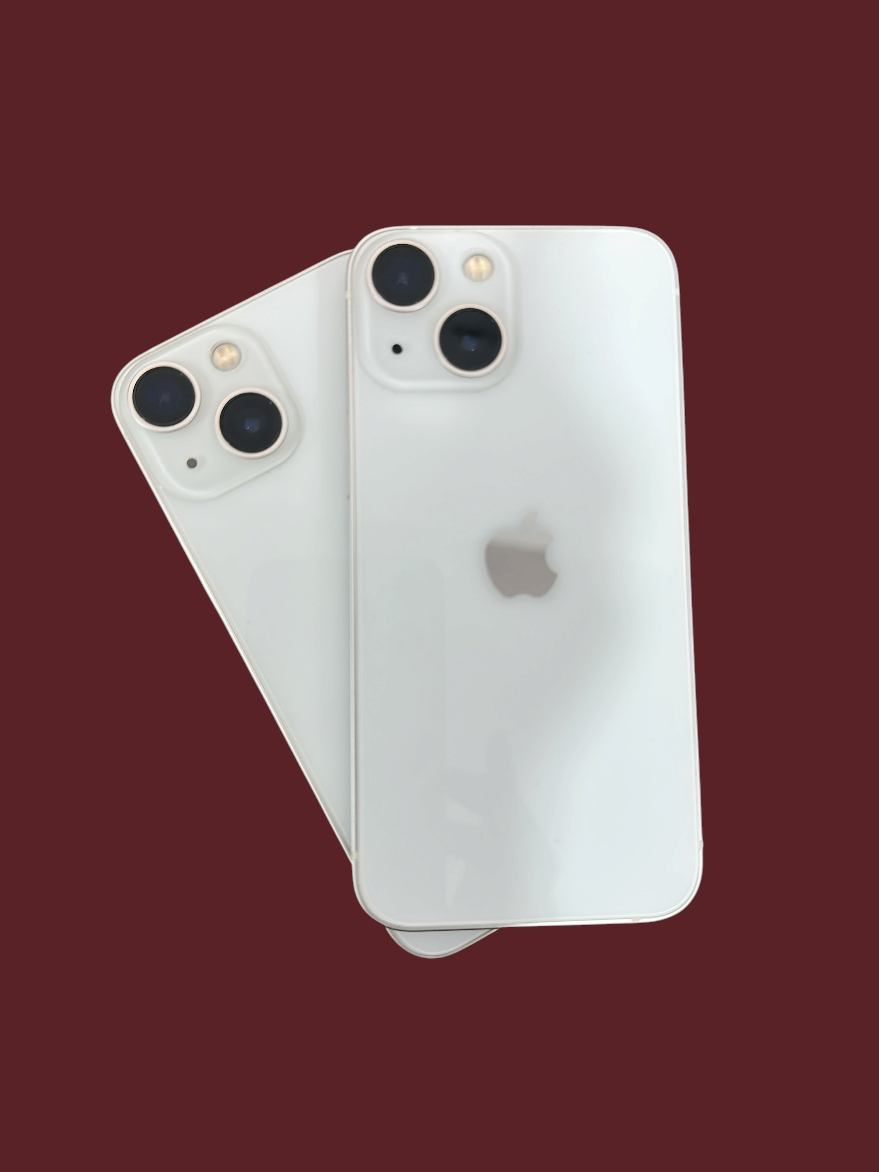 Two white Iphoneio Official smartphones with dual-camera systems and glass backs isolated on a black background