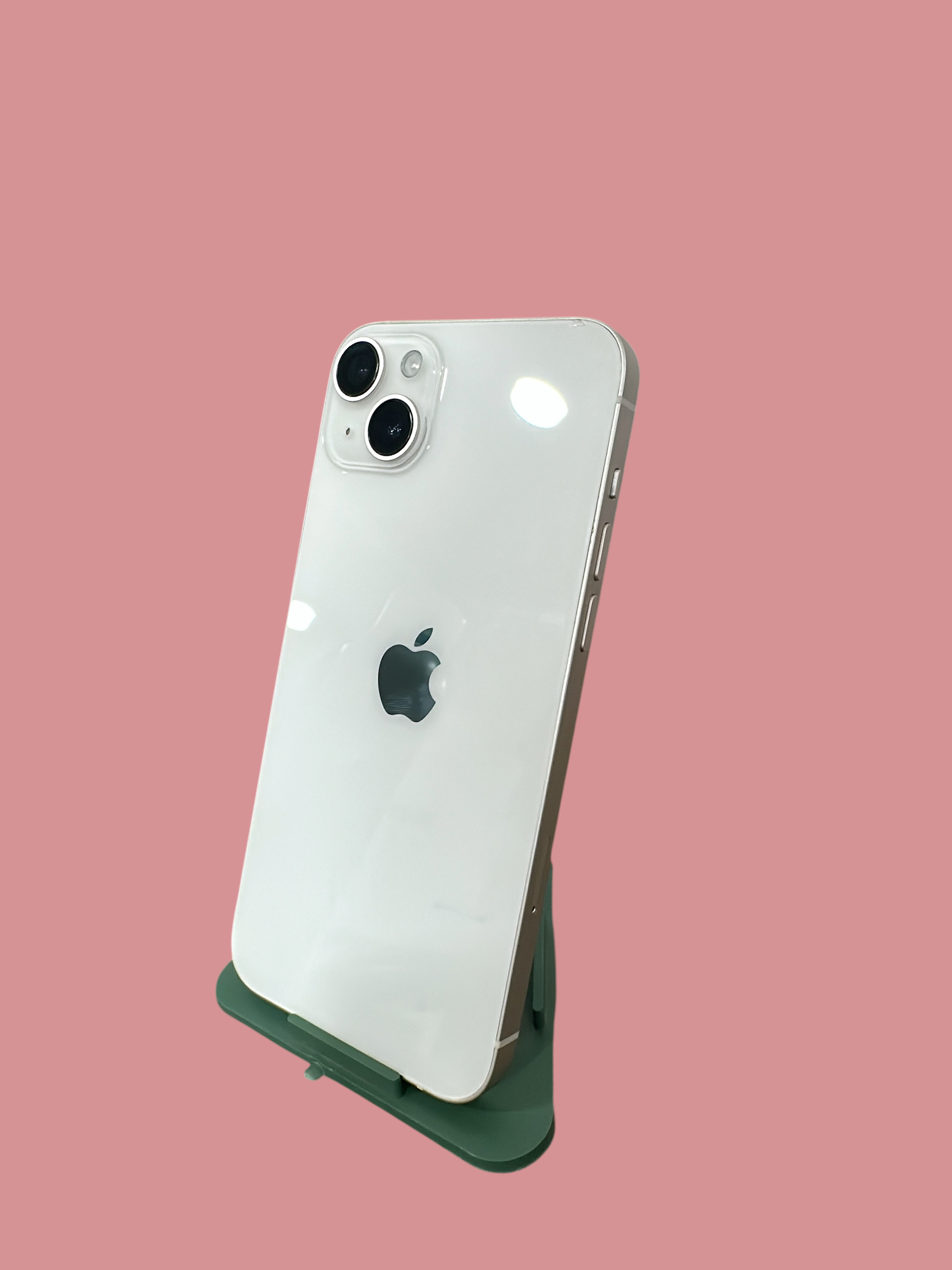 Iphoneio Official white smartphone with a dual-camera system and glass back, displayed on a green stand.